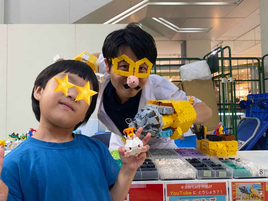 LaQ博士(ハカセイエロー)とイベントで記念撮影する様子